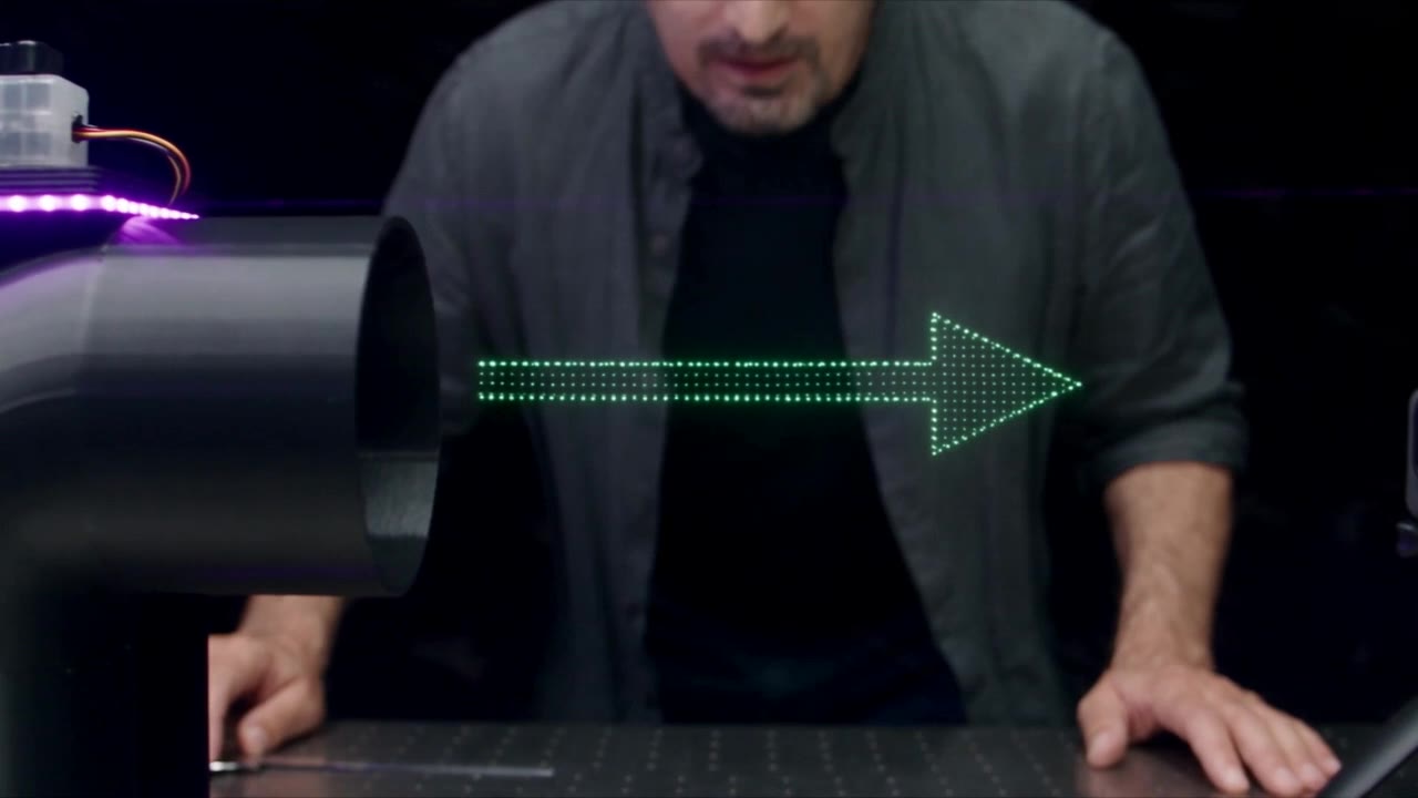 A small arrow made of green light points floating in front of the opening of an air duct.
