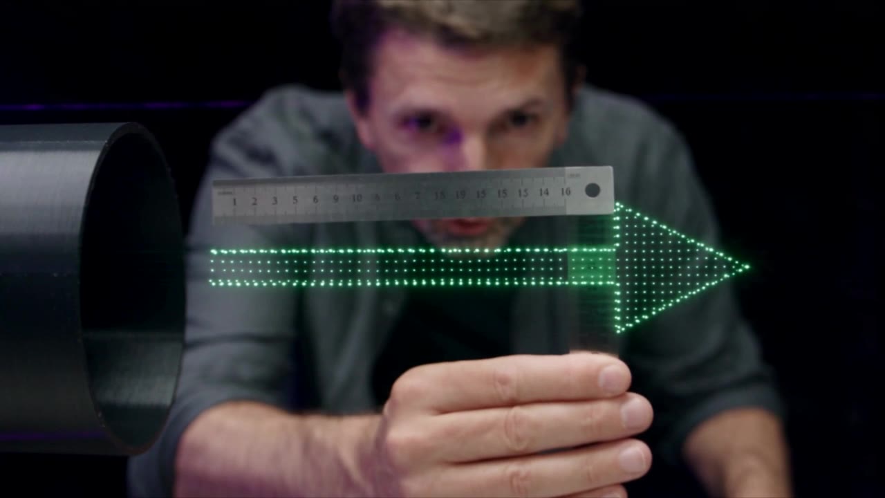 A steel ruler held next to the floating arrow of light points.