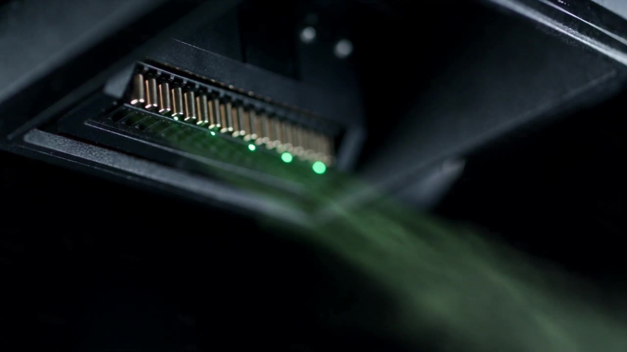 Macro view of an inkjet nozzle plate firing a fine stream of glowing droplets.